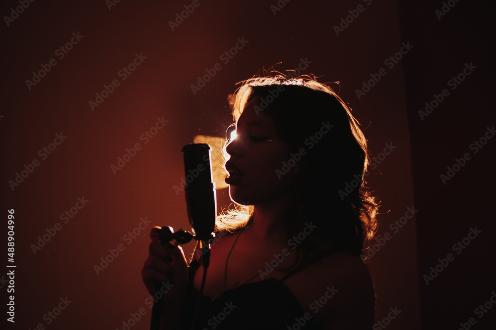 Fototapeta premium silueta de Joven cantante apasionada a contraluz