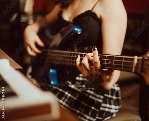 manos de mujer tocando el bajo en un estudio