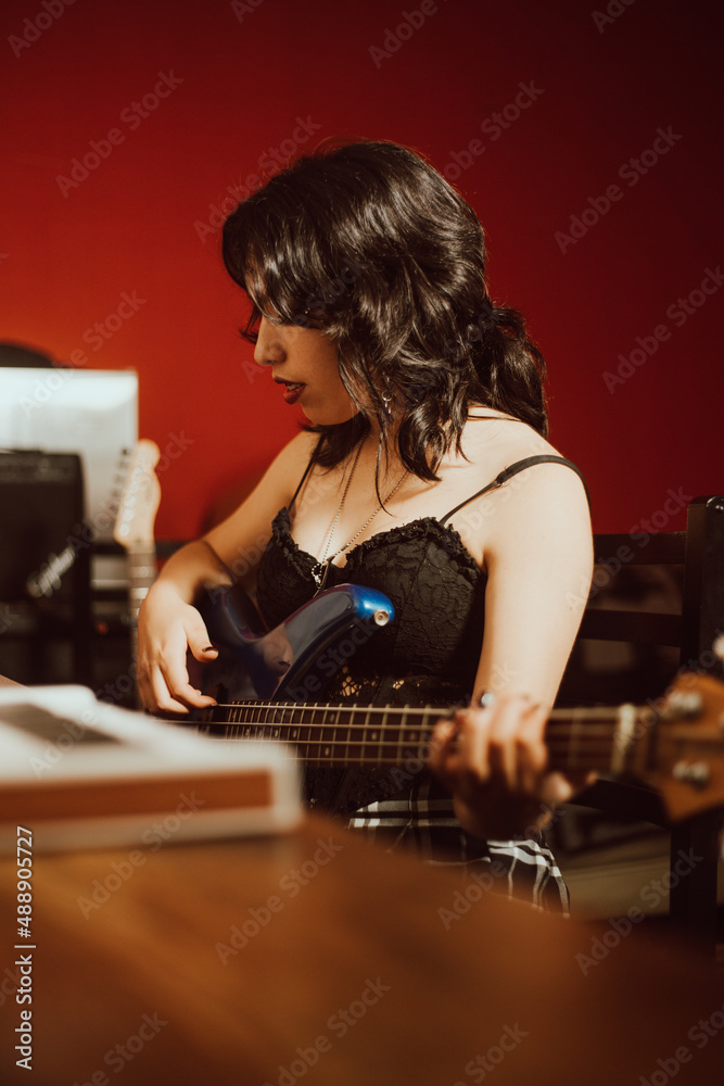 Joven mujer tocando el bajo en un estudio musical Joven mujer tocando el bajo en un estudio musical