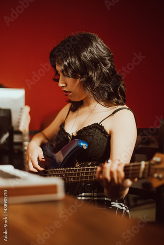 Joven mujer tocando el bajo en un estudio musical