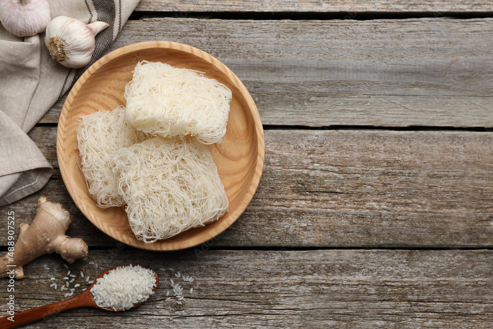 Bowl with dried rice noodles and ingredients on wooden table, flat lay. Space for text Bowl with dried rice noodles and ingredients on wooden table, flat lay. Space for text