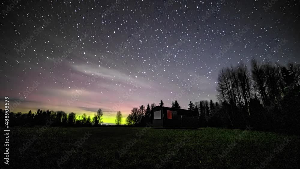 Timelapse shot of flying stars at night sky over rural winter landscape with wooden house with trees in the background. Timelapse shot of flying stars at night sky over rural winter landscape with wooden house with trees in the background.
