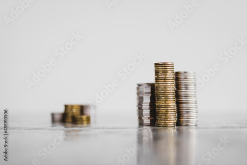 stacks of different coins divided between a small and a big group on white background, good vs bad investements or before and after investing photo