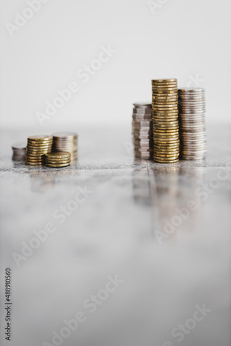 stacks of different coins divided between a small and a big group on white background, good vs bad investements or before and after investing photo