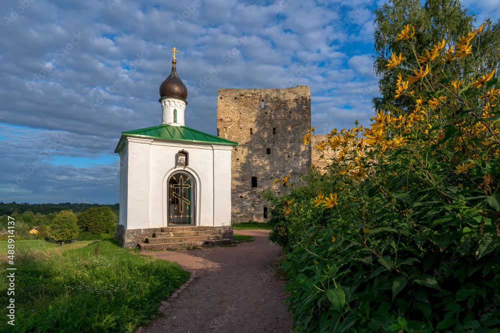 View of the Chapel of the Korsunskaya Icon of the Mother of God against the background of the Talavskaya Tower and the wall of the Izborsk fortress on a sunny summer day, Izborsk, Pskov region