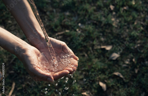 Closeup water flow to hand of women for nature concept on the garden background.