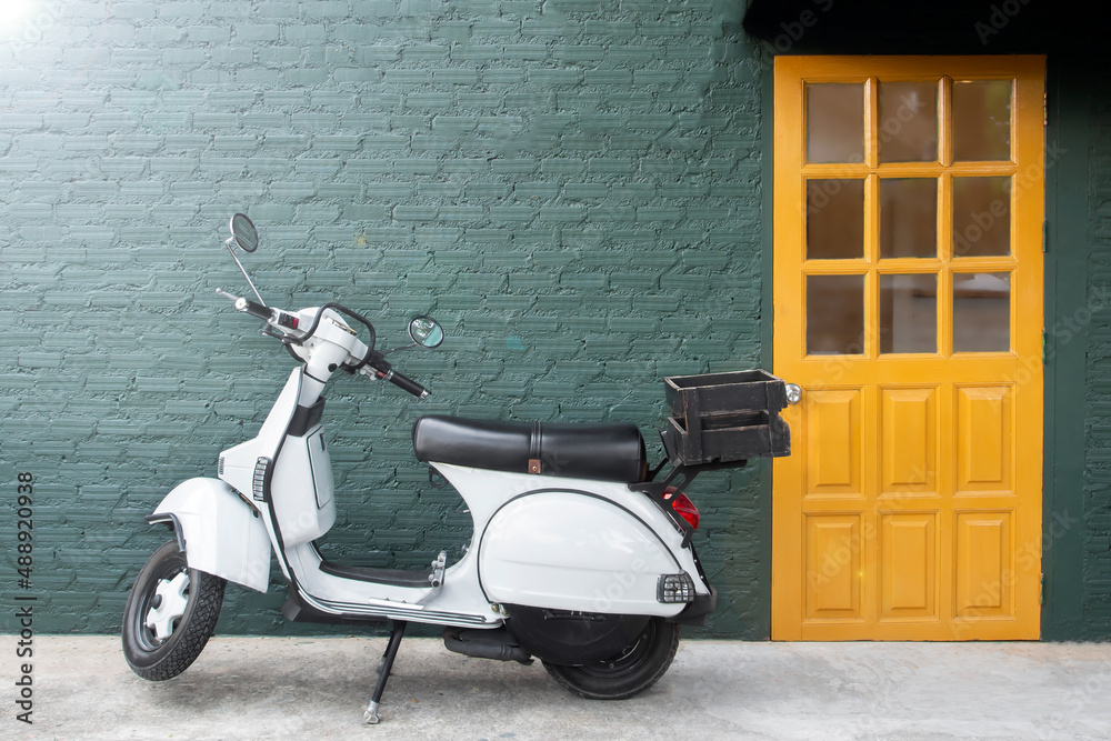 vintage style motorcycle park on the concrete floor in front of green brick wall and fresh yellow door beside