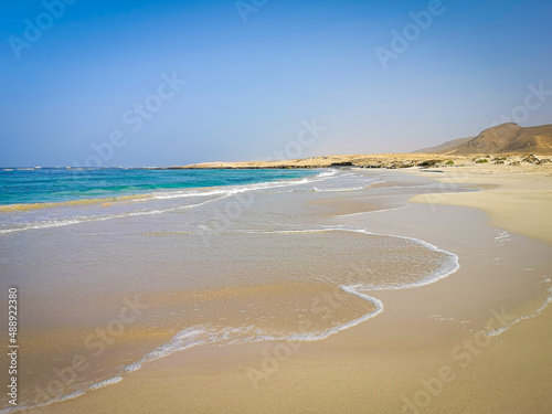Fototapeta Naklejka Na Ścianę i Meble -  Wild Cape Verde bay in winter. Clear blue sky, bright ocean water, small waves, romantic African view. Selective focus on the details, blurred background.