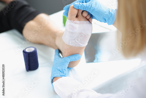 Doctor hand touches and examines wound on leg