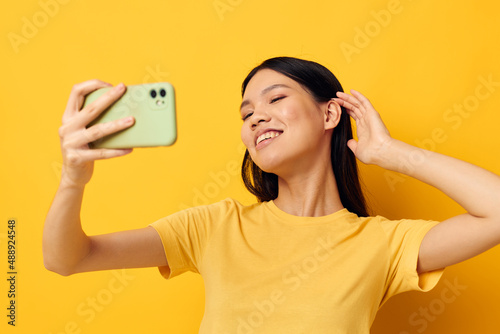woman with Asian appearance in a yellow t-shirt looking at the phone posing Monochrome shot