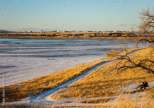 a couple sitting near the winter lake in the park 