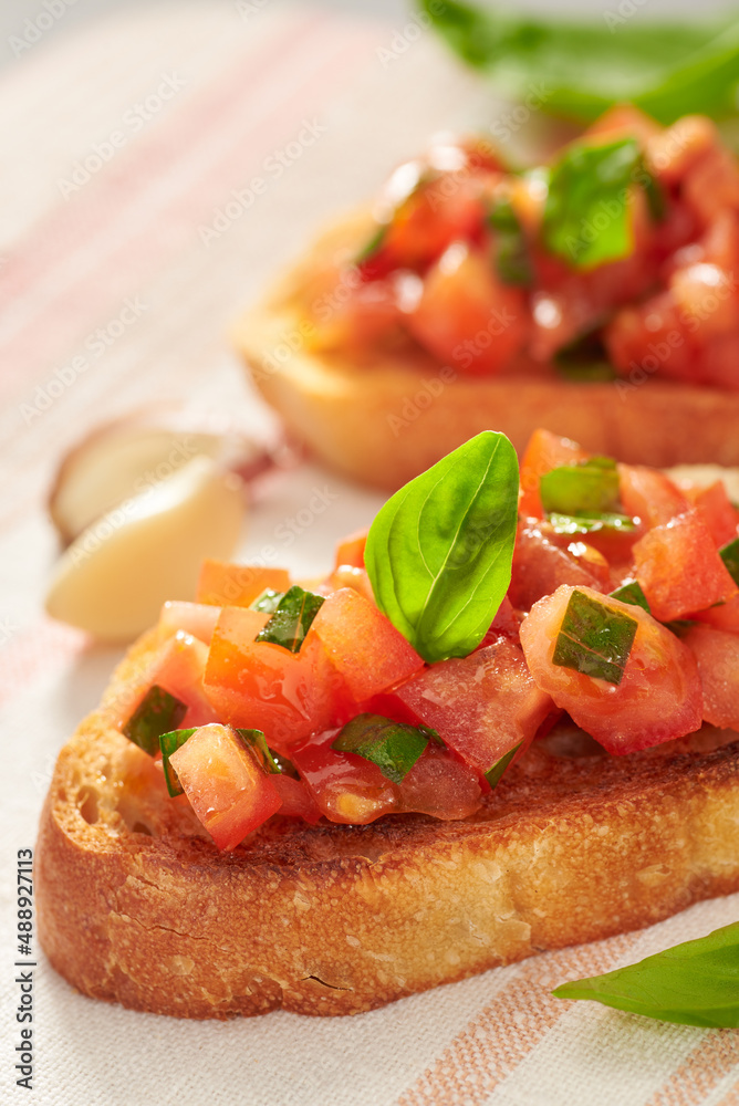 Classic bruschetta – healthy vegetarian Italian snack in a morning or evening light on a gray table. Vertical photo with place for your text. Shallow depth of field.