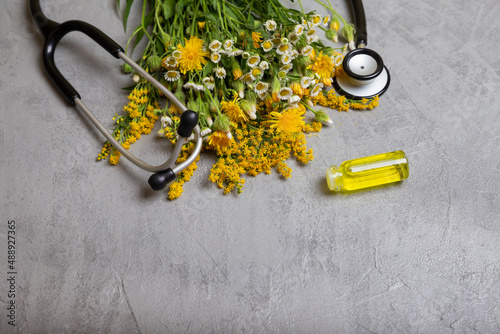 Bunch of healing herbs on concrete table. Essential herbal oil in a glass bottle. Cosmetic organic essential oil. Herbal medicine bottle with flowers. Fresh herbs from the garden for aromatherapy.