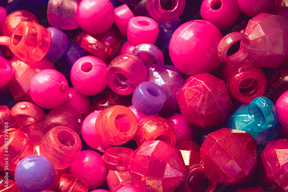 Pink, purple and blue plastic ornamental beads in different shapes are together. Vintage colors background photo of beads. Pink, purple and blue plastic ornamental beads in different shapes are together. Vintage colors background photo of beads.