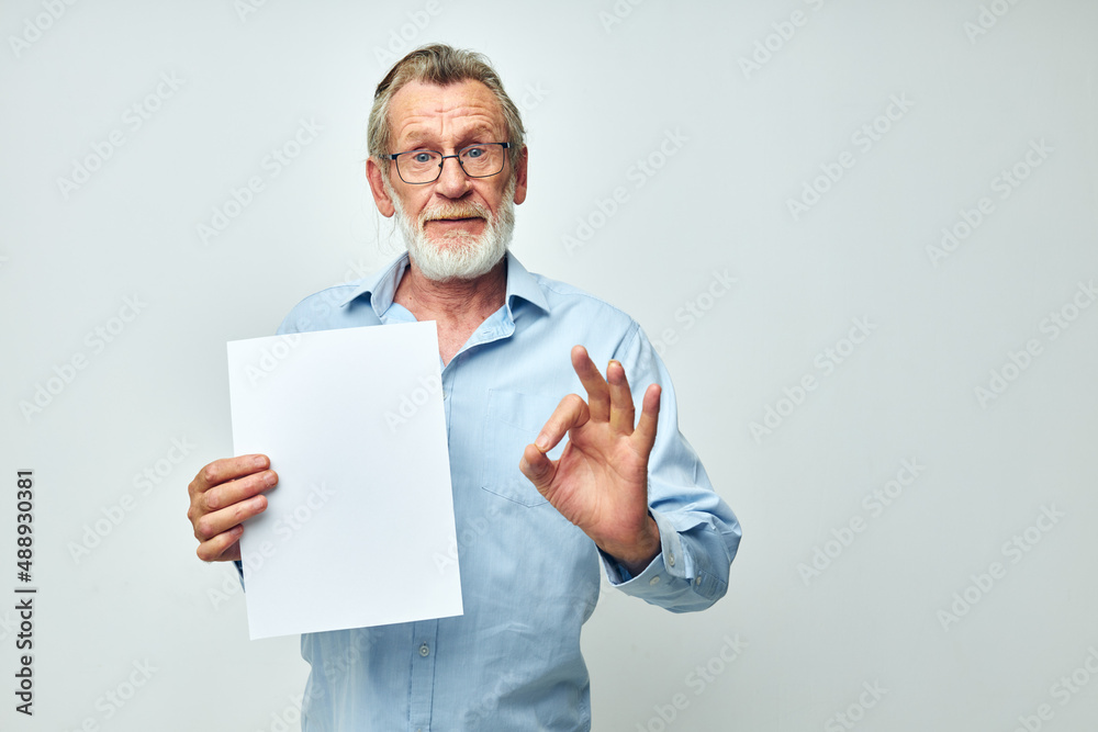 Senior grey-haired man holding a sheet of paper copy-space posing isolated background Senior grey-haired man holding a sheet of paper copy-space posing isolated background