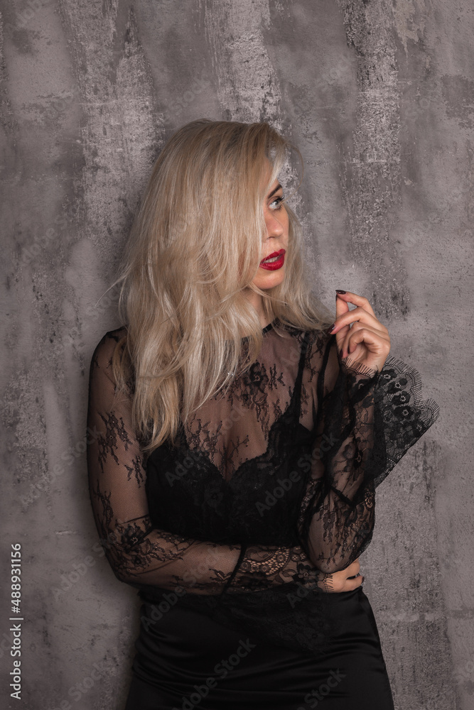 Obraz premium Attractive young woman wearing black dress on grey background