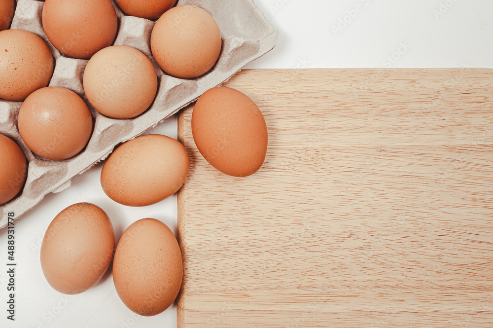 The eggs on the paper tray and wooden chopping board. The eggs on the paper tray and wooden chopping board.