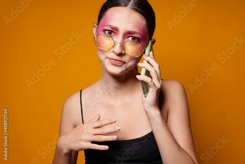 Portrait of beautiful young woman with a phone in hand bright makeup posing fashion emotions close-up unaltered