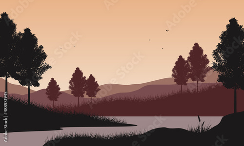 Beautiful mountain view from the lakeside at dusk with silhouettes of pine trees around