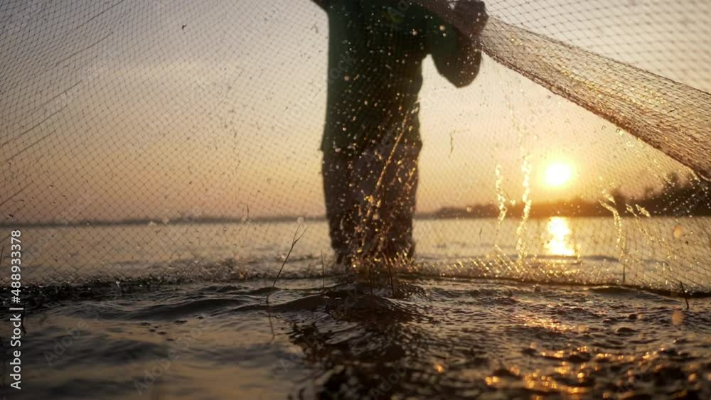 Slow motion shot, Asian Senior Fisherman wearing eyeglasses standing in water and fishing net to fishing at river in early morning