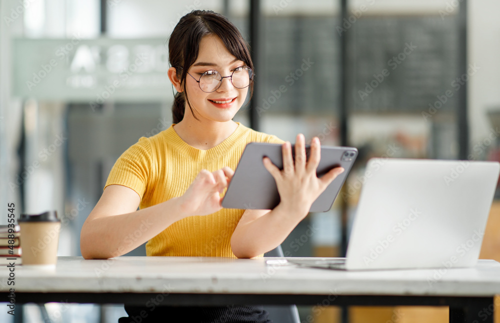 Asian young Businesswoman working and report analyzing financial figures on a graph on a tablet laptop computer sitting in modern coffe shop Asian young Businesswoman working and report analyzing financial figures on a graph on a tablet laptop computer sitting in modern coffe shop