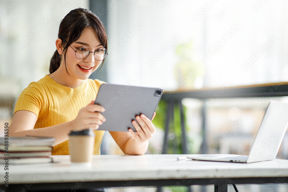 Asian young Businesswoman working and report analyzing financial figures on a graph on a tablet laptop computer sitting in modern coffe shop Asian young Businesswoman working and report analyzing financial figures on a graph on a tablet laptop computer sitting in modern coffe shop