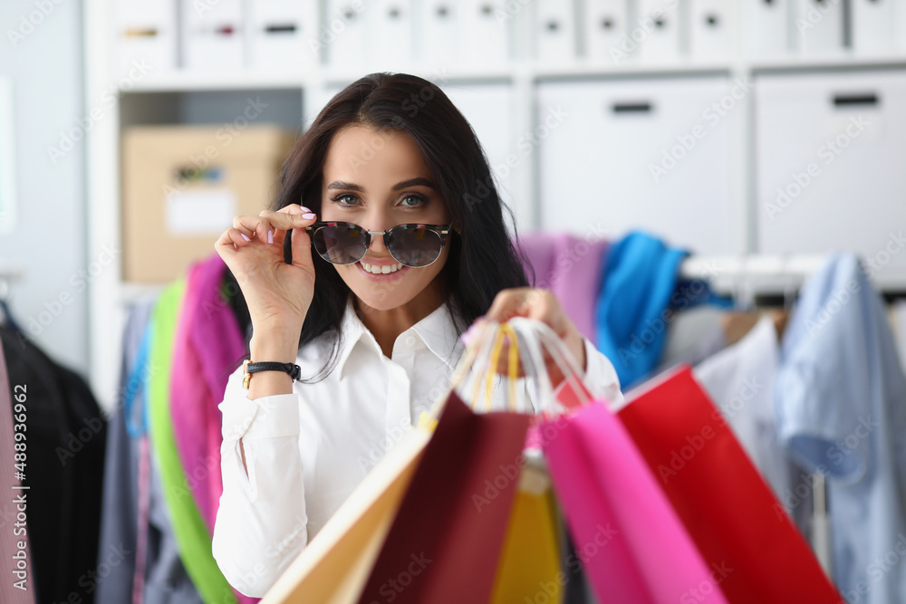 Happy smiling shopaholic woman carry packages with clothes, female holding many packs Happy smiling shopaholic woman carry packages with clothes, female holding many packs