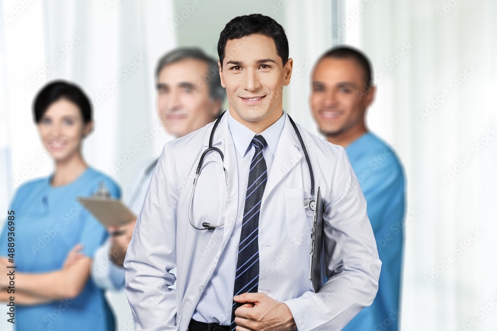 Portrait of happy young nurse in uniform with healthcare team in background. Successful doctor and nurses Portrait of happy young nurse in uniform with healthcare team in background. Successful doctor and nurses