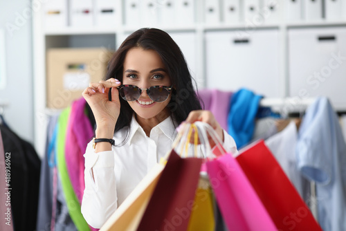 Happy smiling shopaholic woman carry packages with clothes, female holding many packs