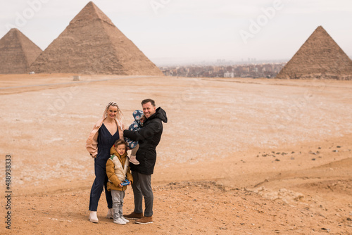 happy tourist family in Giza. holiday travel tpur near Pyramid of Khafre, Egypt. Windy weather.Parent with 2 kids on piramids