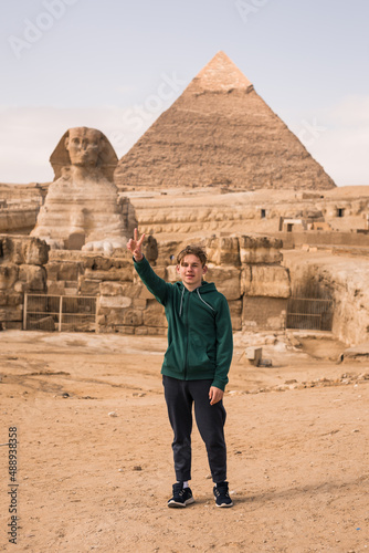 man against the background of the Egyptian pyramids. Hand up.