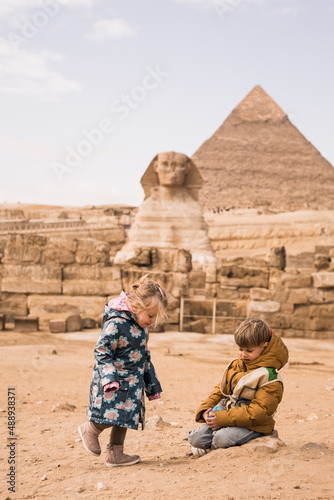 happy little girl and boy plaing on background of Great Sphinx and Chephren's pyramid in Giza, Egypt