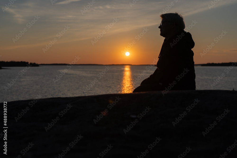 A woman sits on the rocks, on the seashore, he looks at the sunset,. The concept of rest, vacation. A woman sits on the rocks, on the seashore, he looks at the sunset,. The concept of rest, vacation.