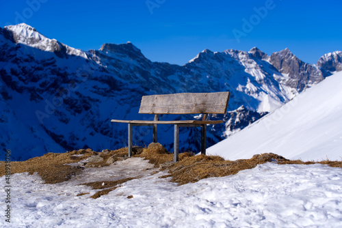 Empty wooden bench at Fürenalp in the Swiss Alps on a sunny winter morning in bright sunlight. Photo taken February 9th, 2022, Engelberg, Switzerland.