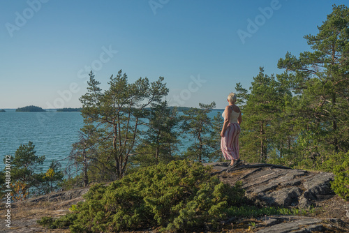 A woman on the rocks  on the seashore  she admires nature . The concept of rest  vacation.