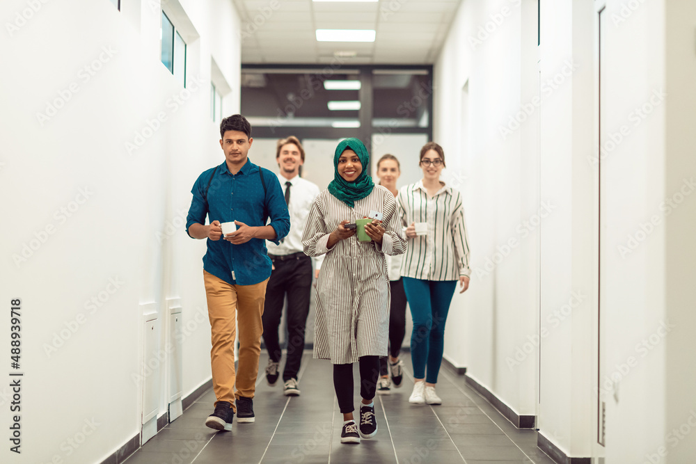 Multi-ethnic startup business team walking through the hallway of the building while coming back from a coffee break Multi-ethnic startup business team walking through the hallway of the building while coming back from a coffee break