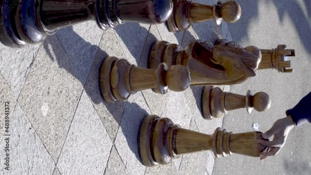 People play giant chess strategy game in public park. VERTICAL format People play giant chess strategy game in public park. VERTICAL format