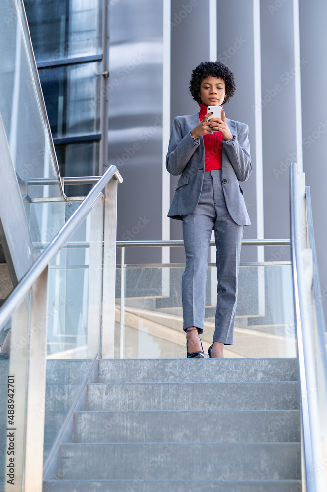 Elegante mujer afroamericana utilizando el teléfono móvil en un edificio de oficinas Elegante mujer afroamericana utilizando el teléfono móvil en un edificio de oficinas