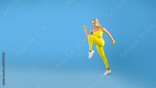 Young Woman Exercising With Dumbbells Isolated On Blue Background