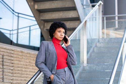 Elegante mujer afroamericana utilizando el teléfono móvil en un edificio de oficinas 