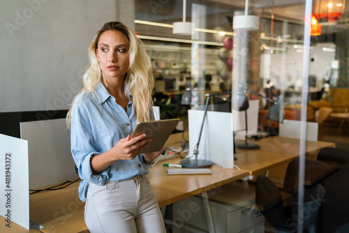 Portrait of an attractive young businesswoman smiling working on digital tablet in office