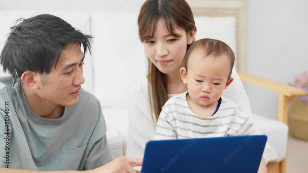 赤ちゃんにノートパソコンを見せる両親