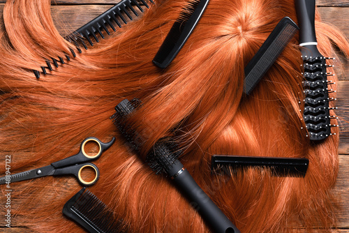Hairdressing salon concept background. Redhead women wig and combs on the hairdresser table flat lay background.