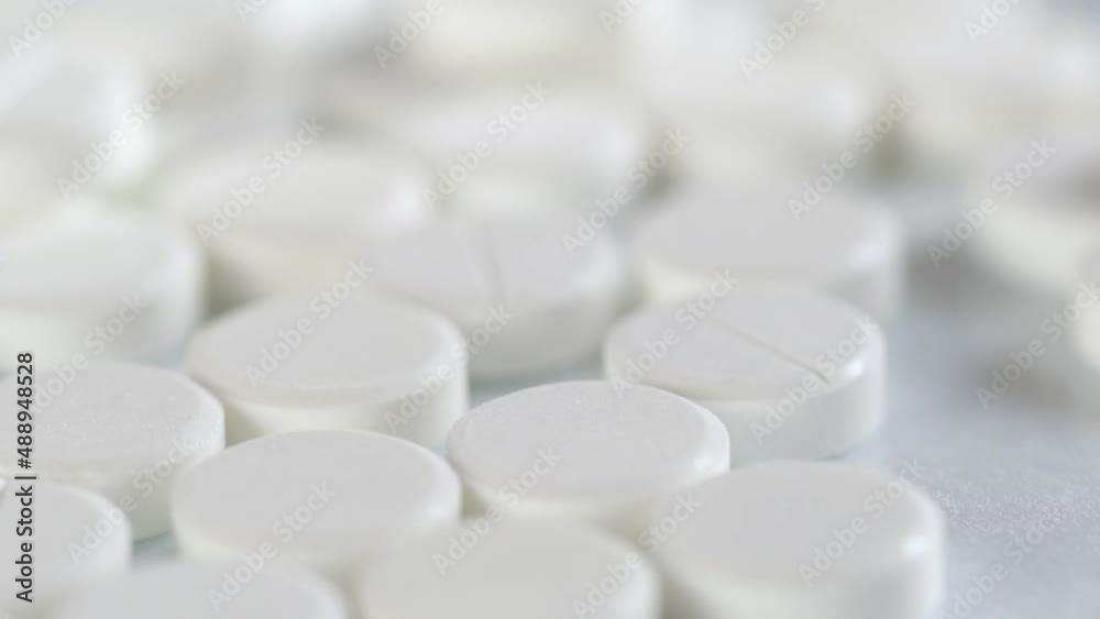 The medicine concept.white medical pills rotating closeup. Pills and drugs. Pharmaceutical Industry.many white round pills. pharmaceutical production. drugs on the production line. moving background The medicine concept.white medical pills rotating closeup. Pills and drugs. Pharmaceutical Industry.many white round pills. pharmaceutical production. drugs on the production line. moving background