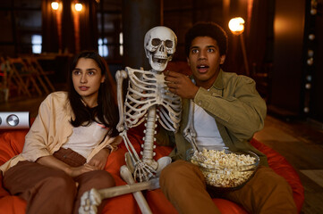 Funny couple and skeleton watching studio projector