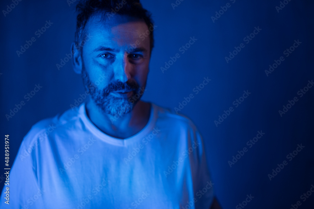 Naklejka premium Depressed mature man, alone in darkness, looking at camera, mental health concept.