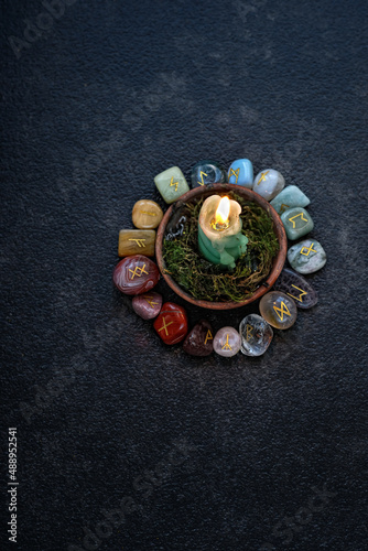 Rune stones with symbols and candle on abstract black background. minerals pebble with rune symbols for fortune telling, prediction destiny. ancient witch and shaman magic ritual. top view