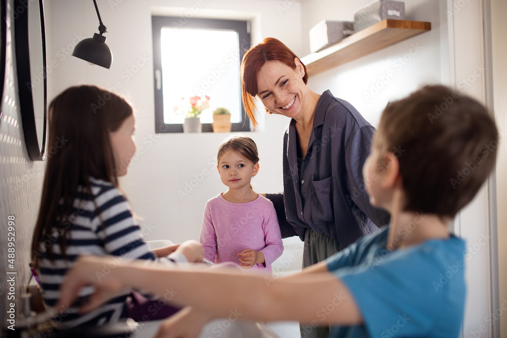 Mother with three little children in bathroom, morning routine concept.
