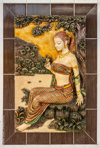 Bas-Relief of beautiful woman wearing sarong in forest. It is a low sculpture which is carved into a wall. photo