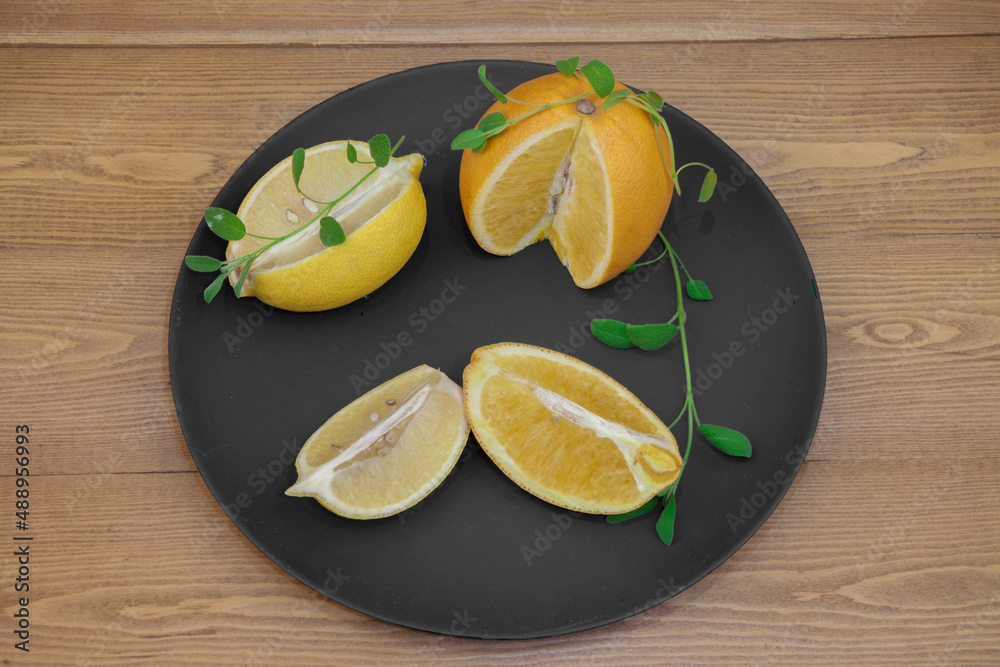 Ripe fruits of a yellow orange. on a black and white plate. Citrus fruits on a platter. Still-life. on a wooden background. top view. close-up.